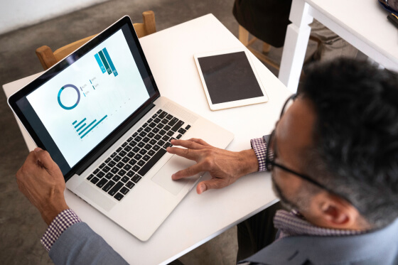 Man on laptop looking at market graphs and insights