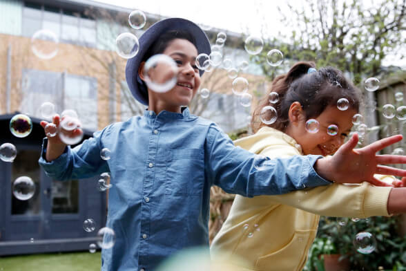 Two diverse kids playing with bubbles outside
